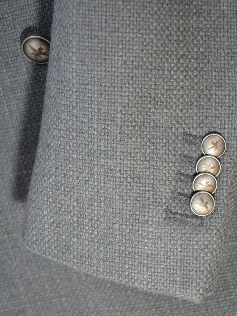 Close-up of a gray textured fabric with buttons on a suit jacket.