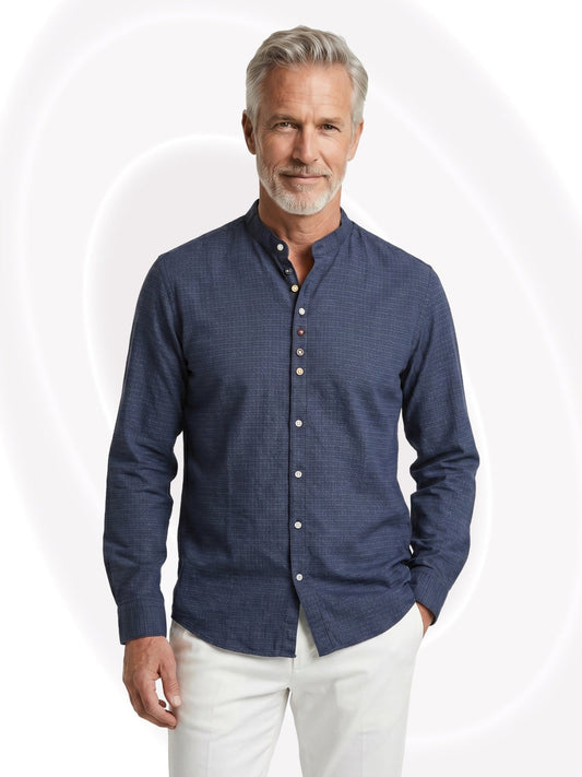 Man wearing a navy textured shirt and white pants on a white background