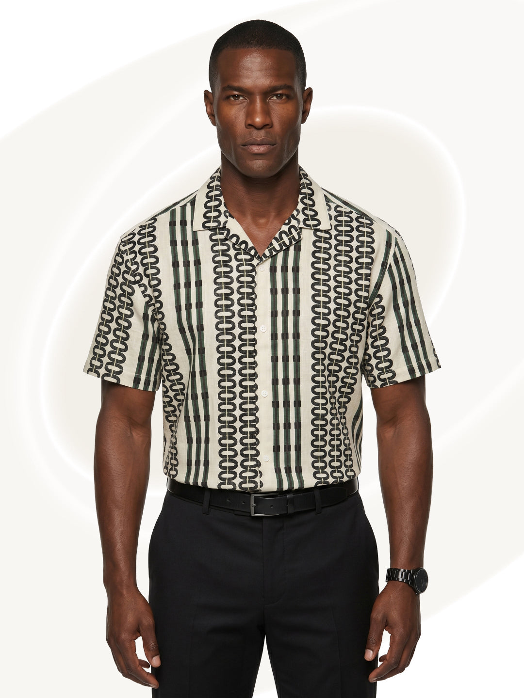 Man wearing a patterned button down shirt and black pants on a white background
