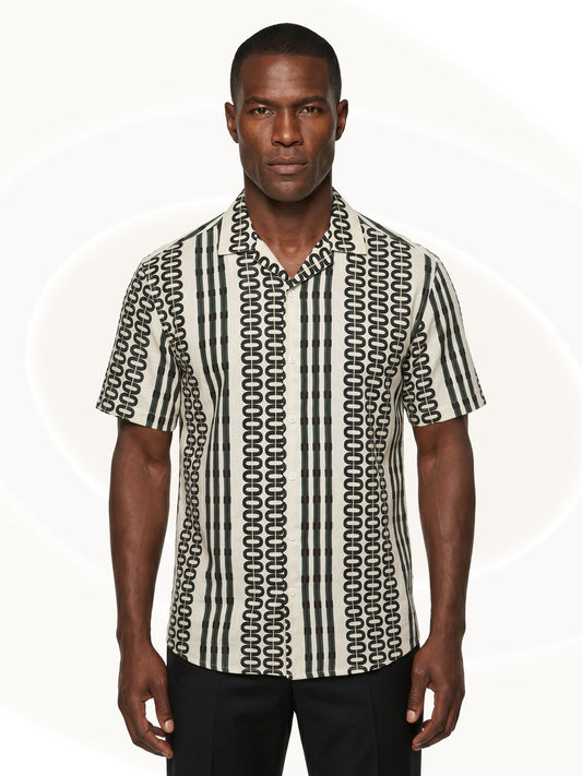 Man wearing a patterned button down shirt and black pants on a white background
