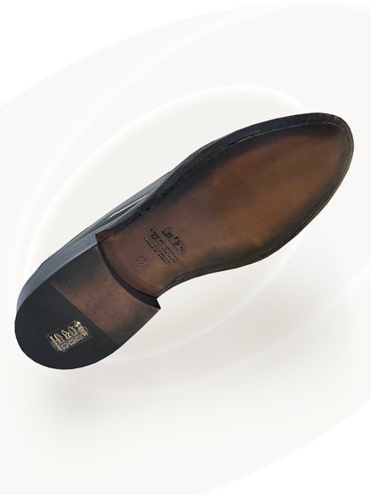 Close-up of a black leather shoe sole with a visible brand logo on a white background
