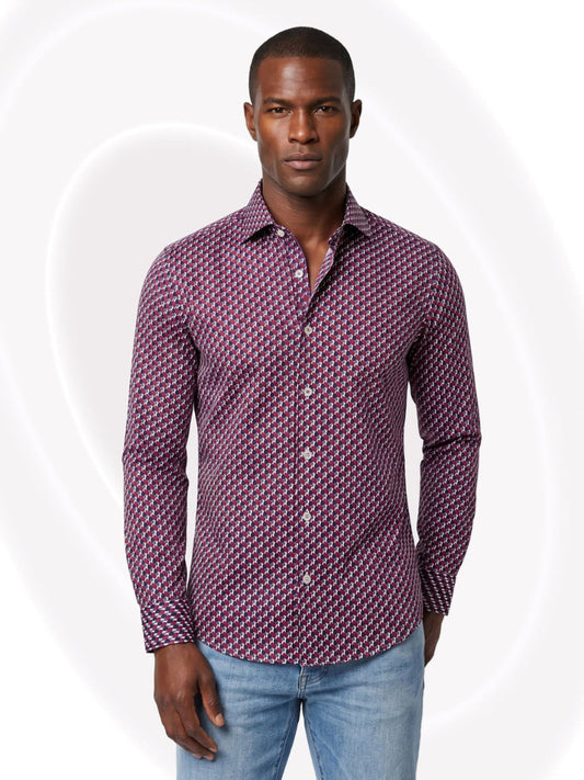 Man wearing a patterned purple shirt and light blue jeans on a white background