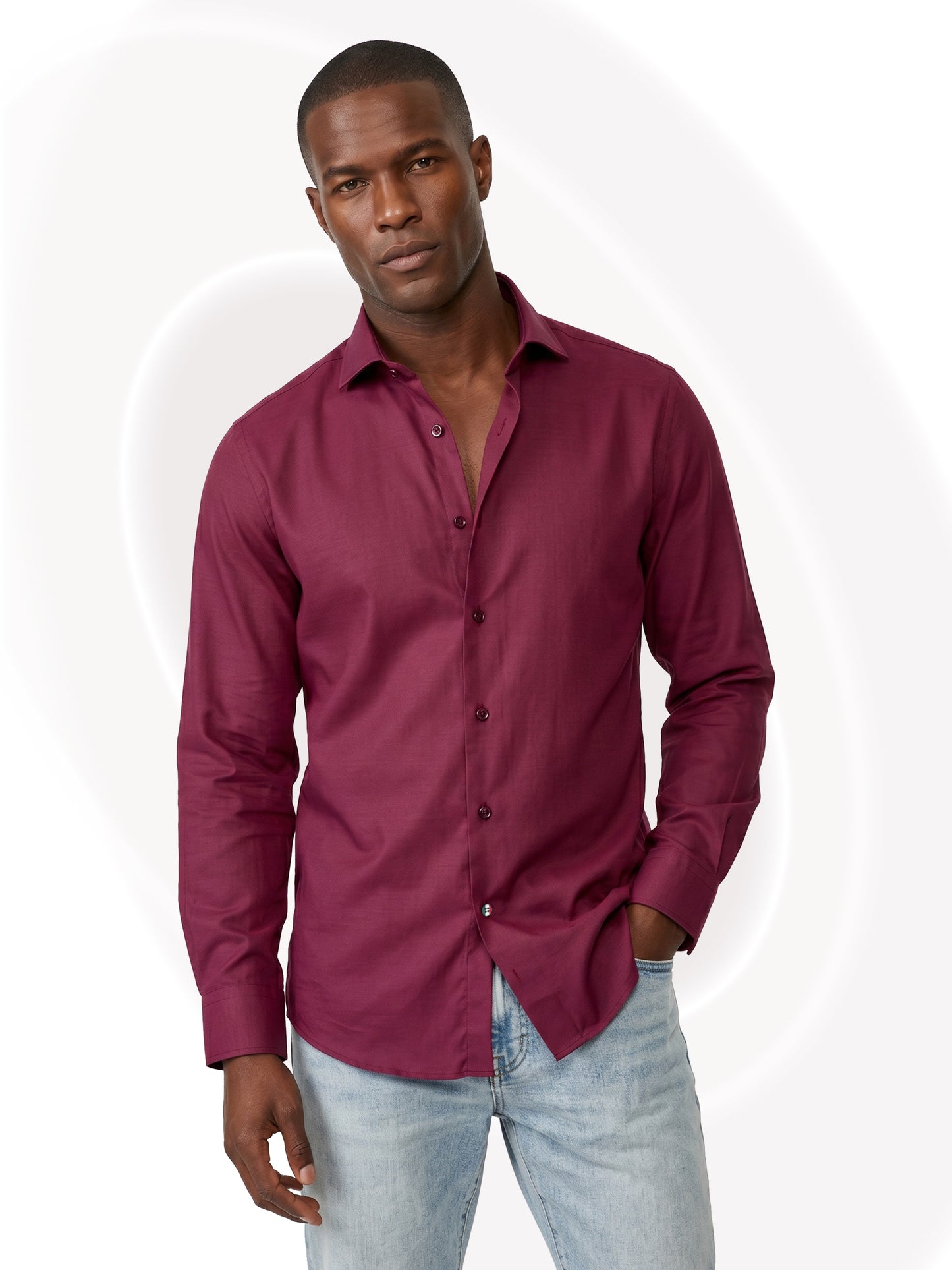 Man wearing a burgundy shirt and light blue jeans on a white background