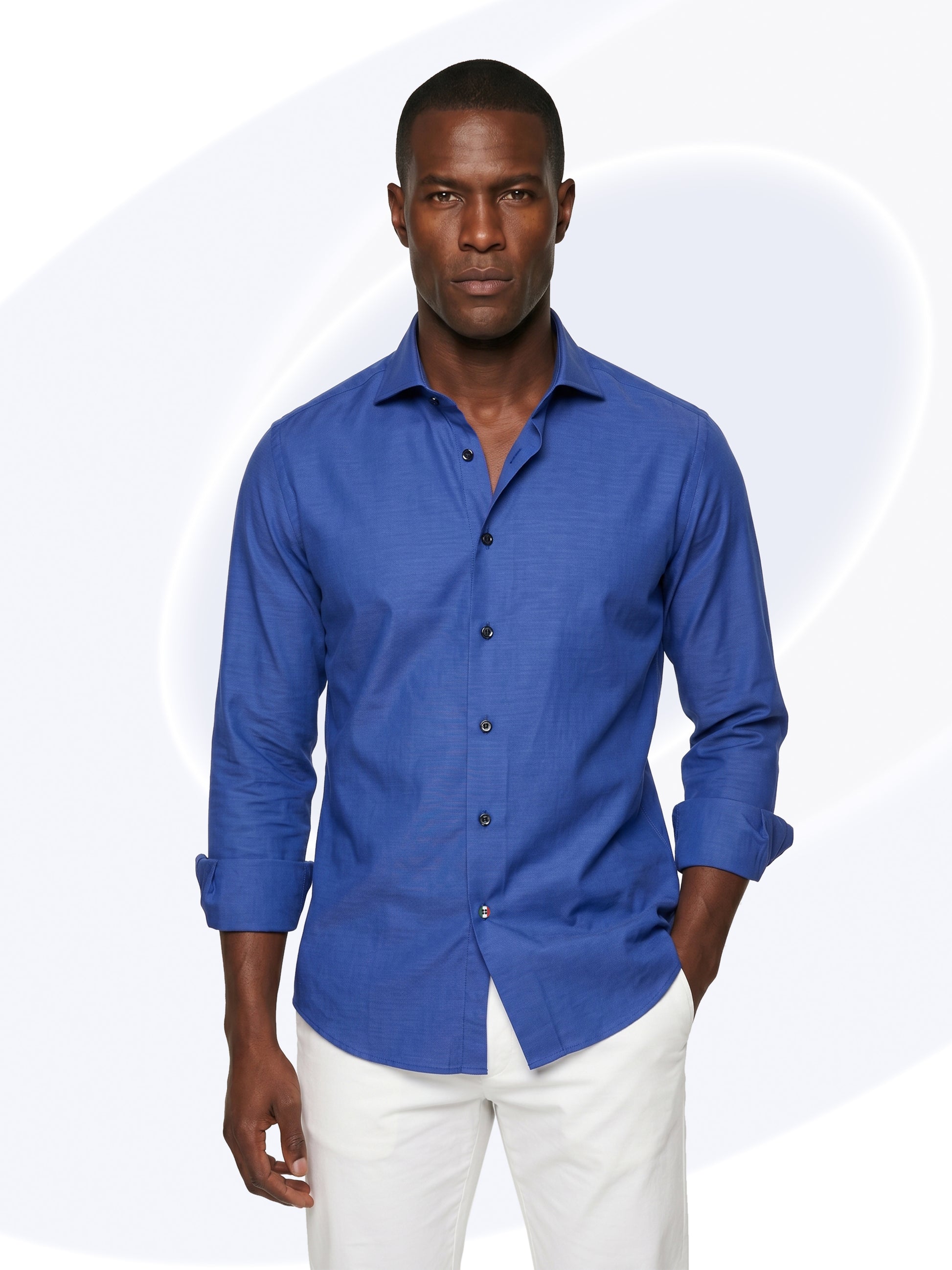 Man wearing a blue shirt and white pants on a white background