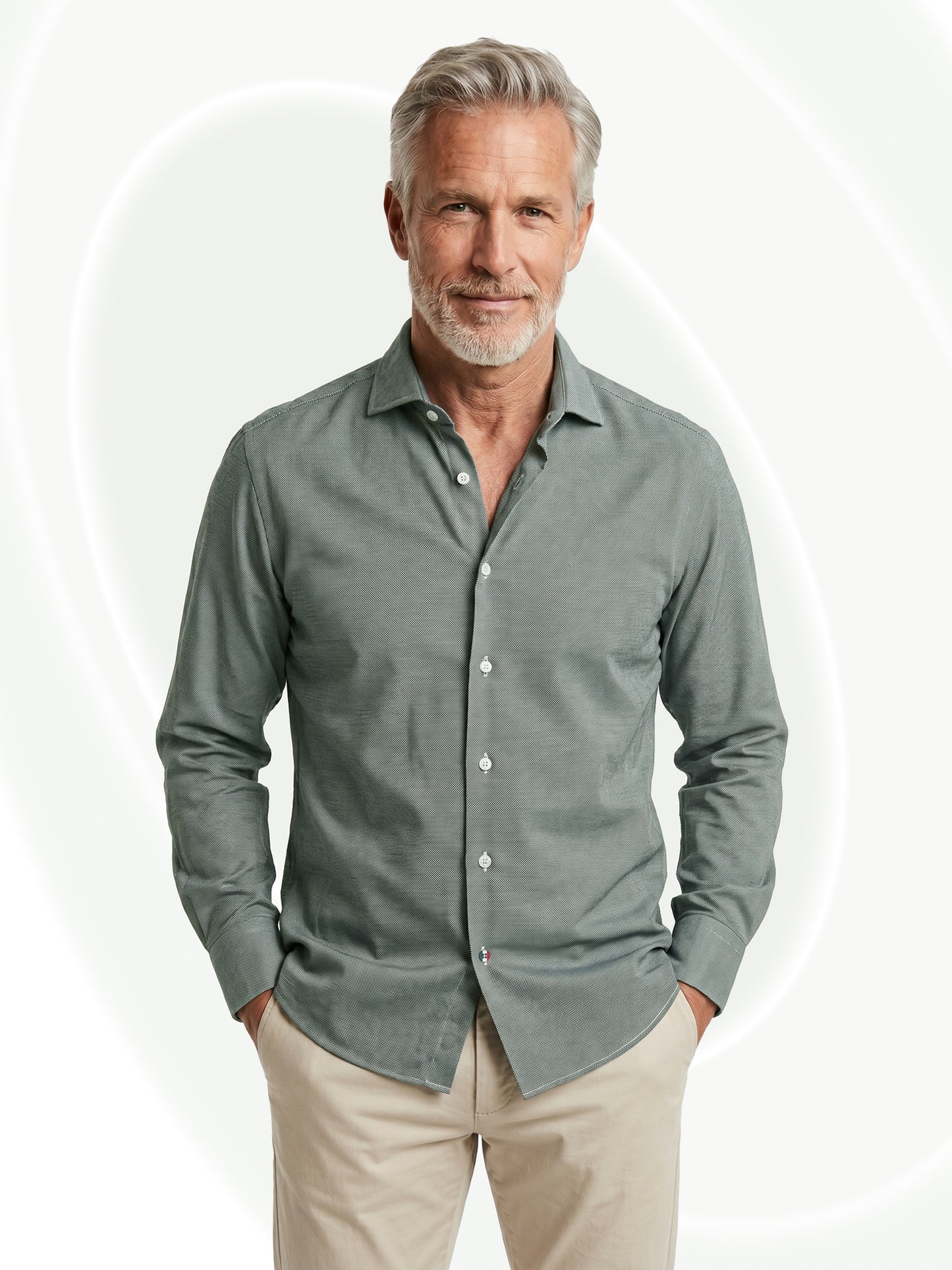 Man wearing a green button-up shirt and beige pants on a white background