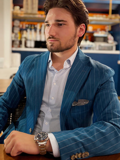 Man wearing a blue pinstripe suit with a watch in an indoor setting