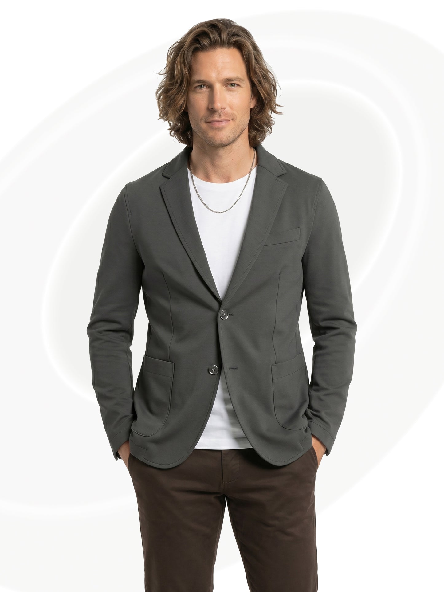 Man wearing a gray blazer over a white shirt with brown pants on a white background