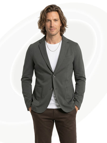 Man wearing a gray blazer over a white shirt with brown pants on a white background
