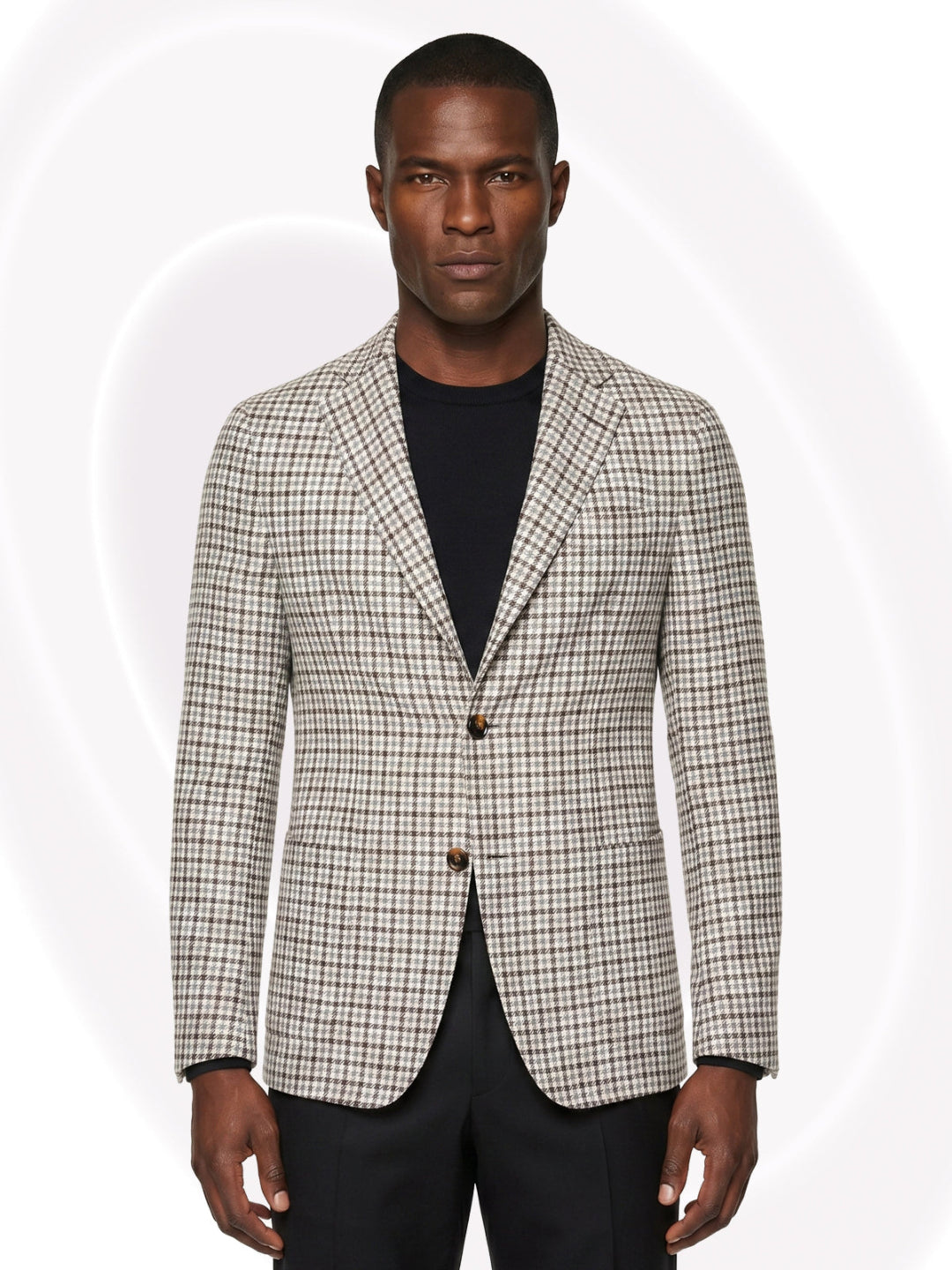 Man wearing a checkered blazer over a black shirt and black pants on a white background