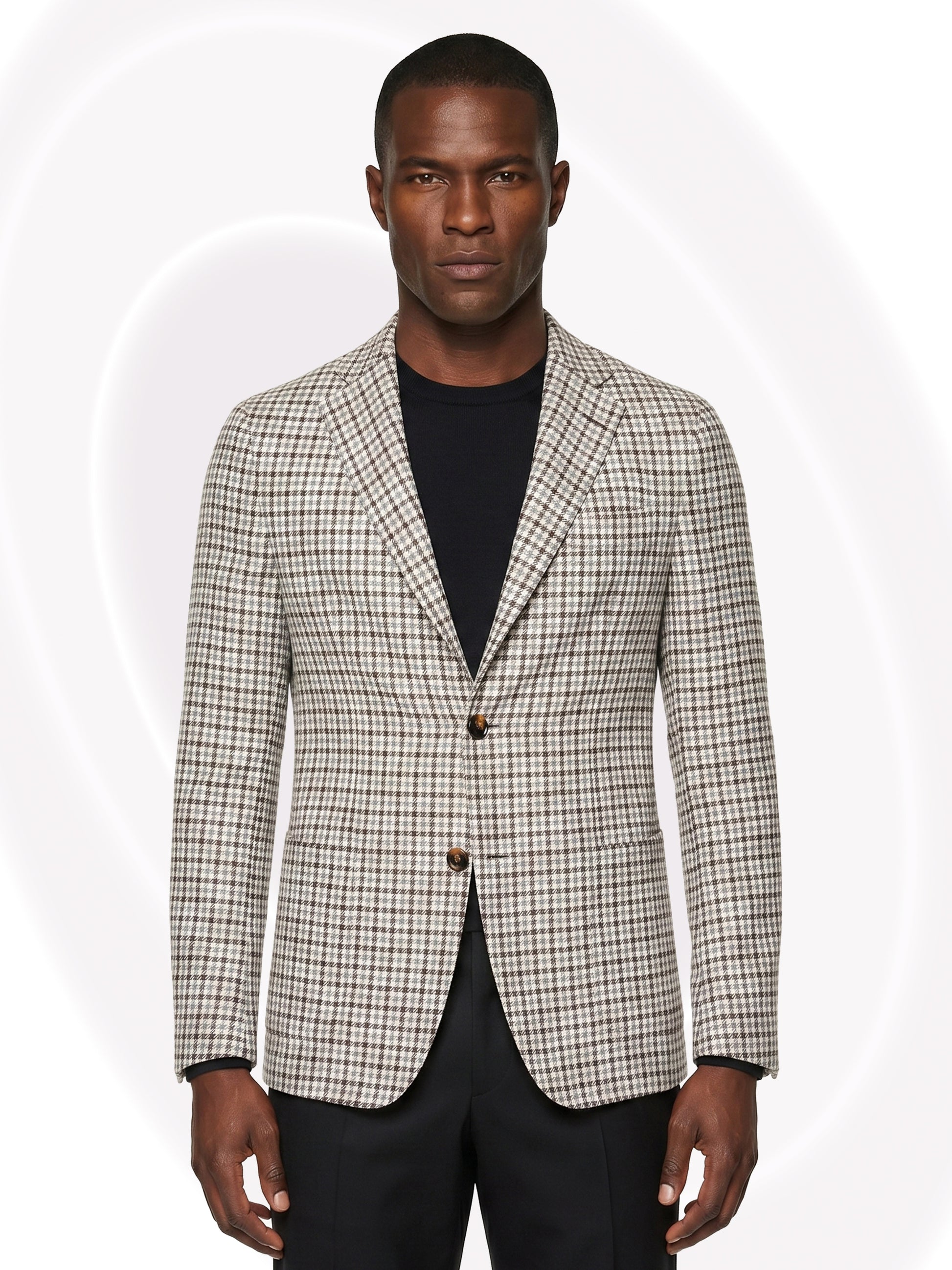 Man wearing a checkered blazer over a black shirt and black pants on a white background