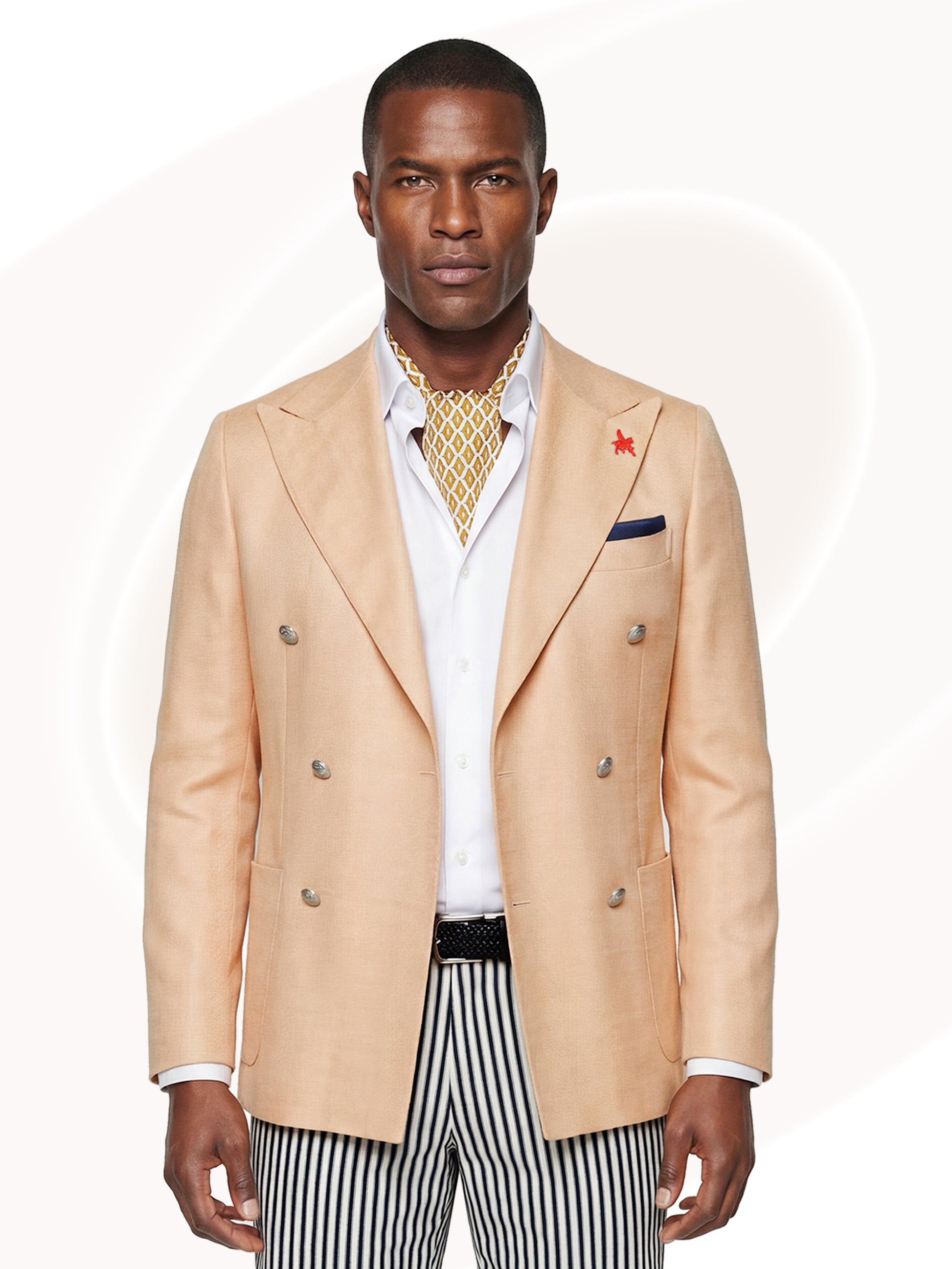 Man wearing light orange blazer over white shirt, gold print tie and striped shorts
