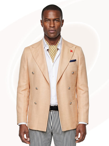 Man wearing light orange blazer over white shirt, gold print tie and striped shorts