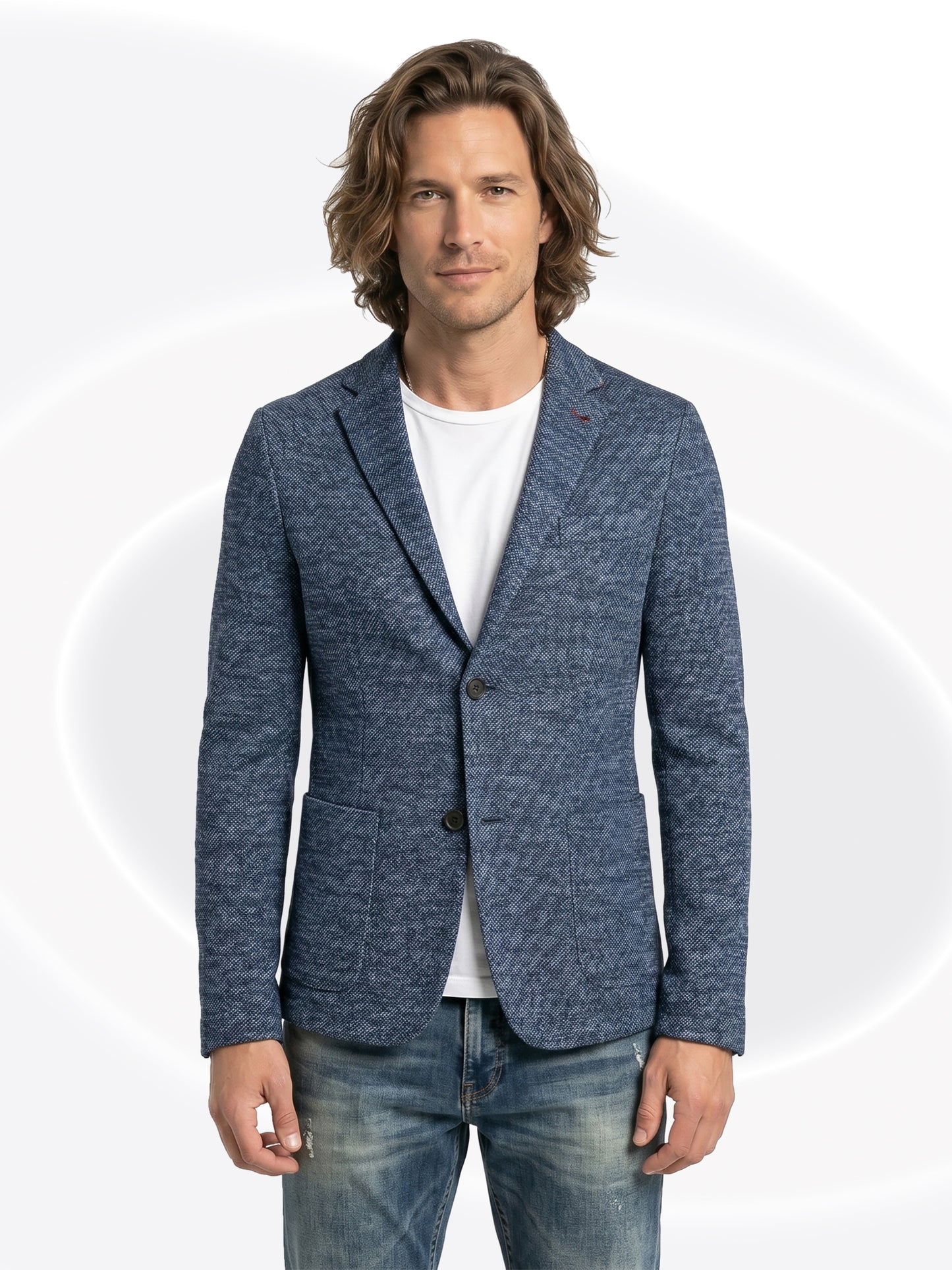 Man wearing a blue blazer over a white shirt and faded jeans with a white background