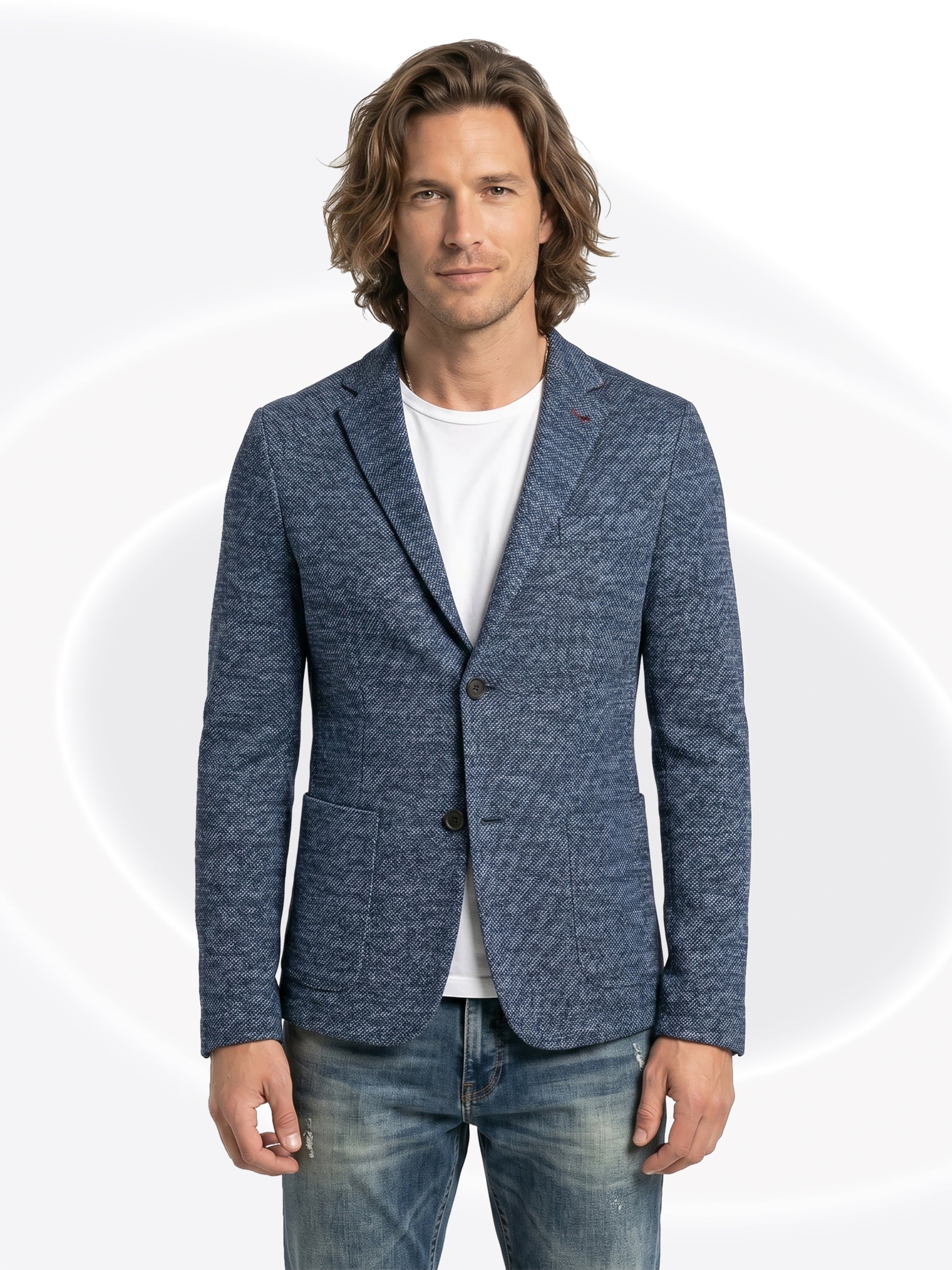 Man wearing a blue blazer over a white shirt and faded jeans with a white background