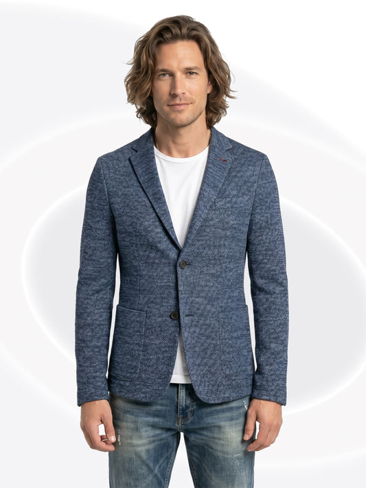 Man wearing a blue blazer over a white shirt and faded jeans with a white background