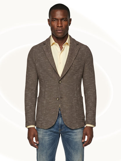 Man wearing a brown fitted blazer over a yellow shirt and blue jeans on a white background