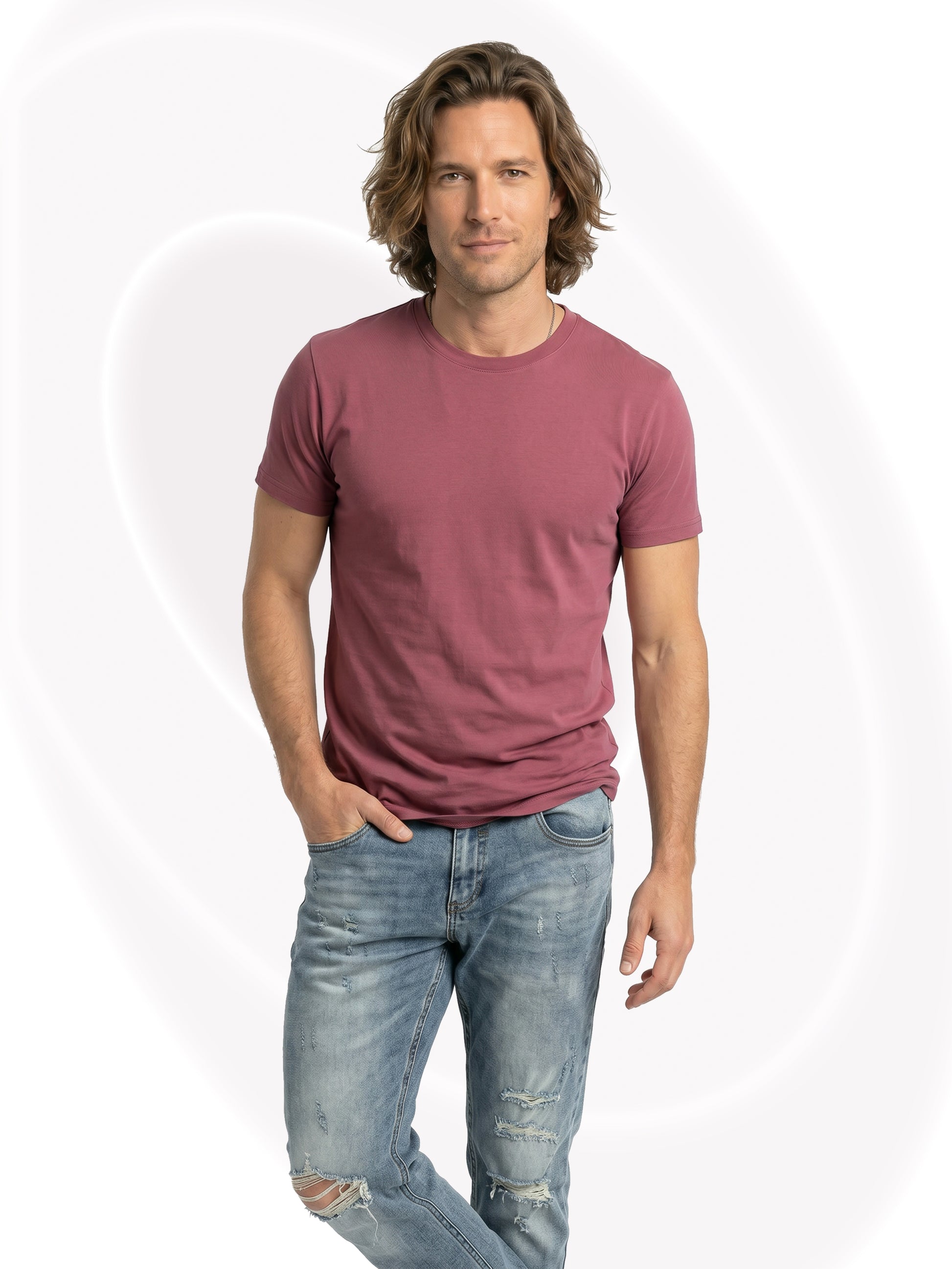 Man wearing a mauve t-shirt and light blue jeans on a white background