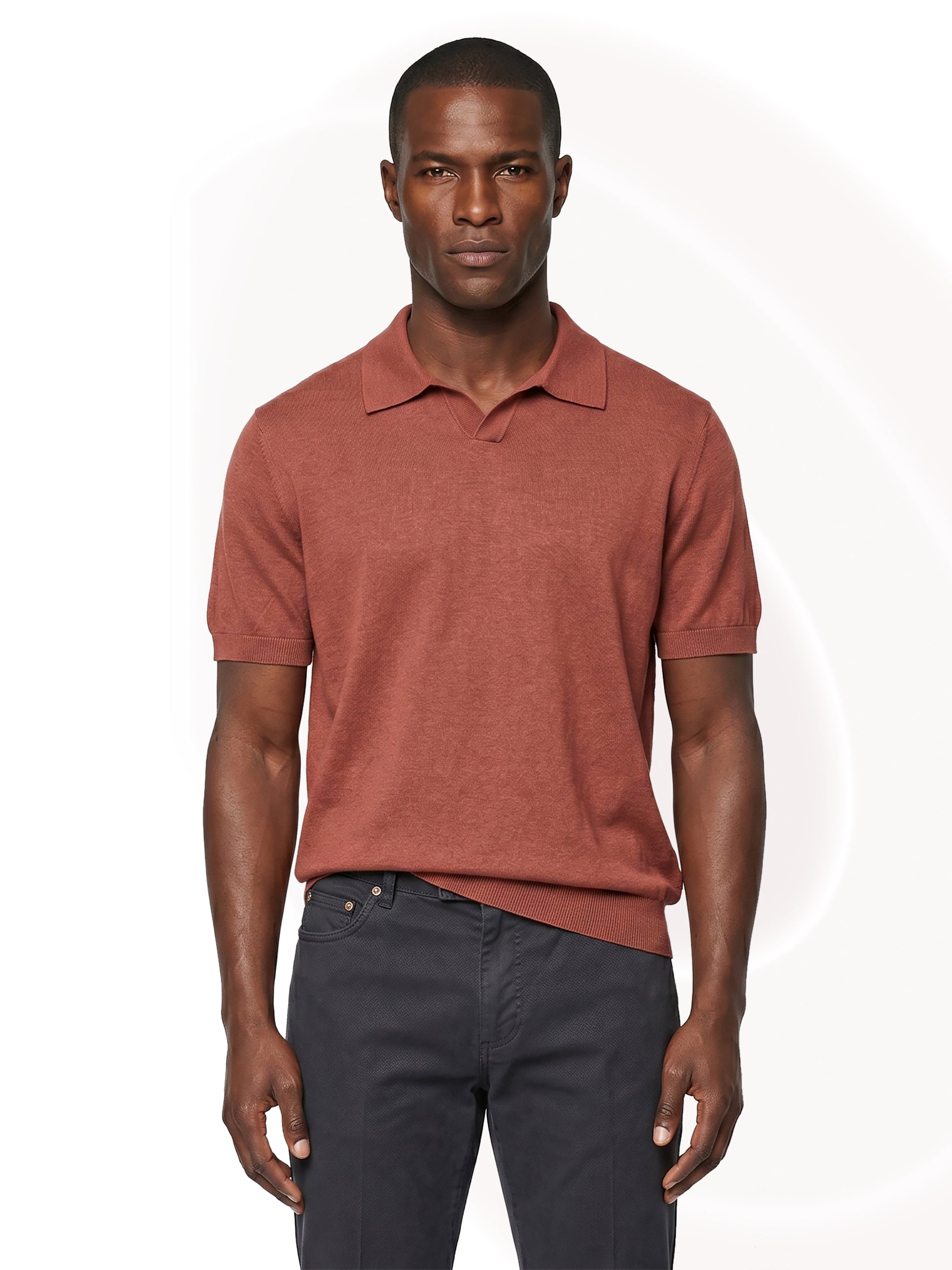 Man wearing a copper polo shirt and dark pants on a white background