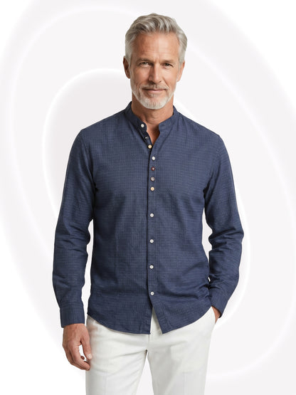 Man wearing a navy textured shirt and white pants on a white background