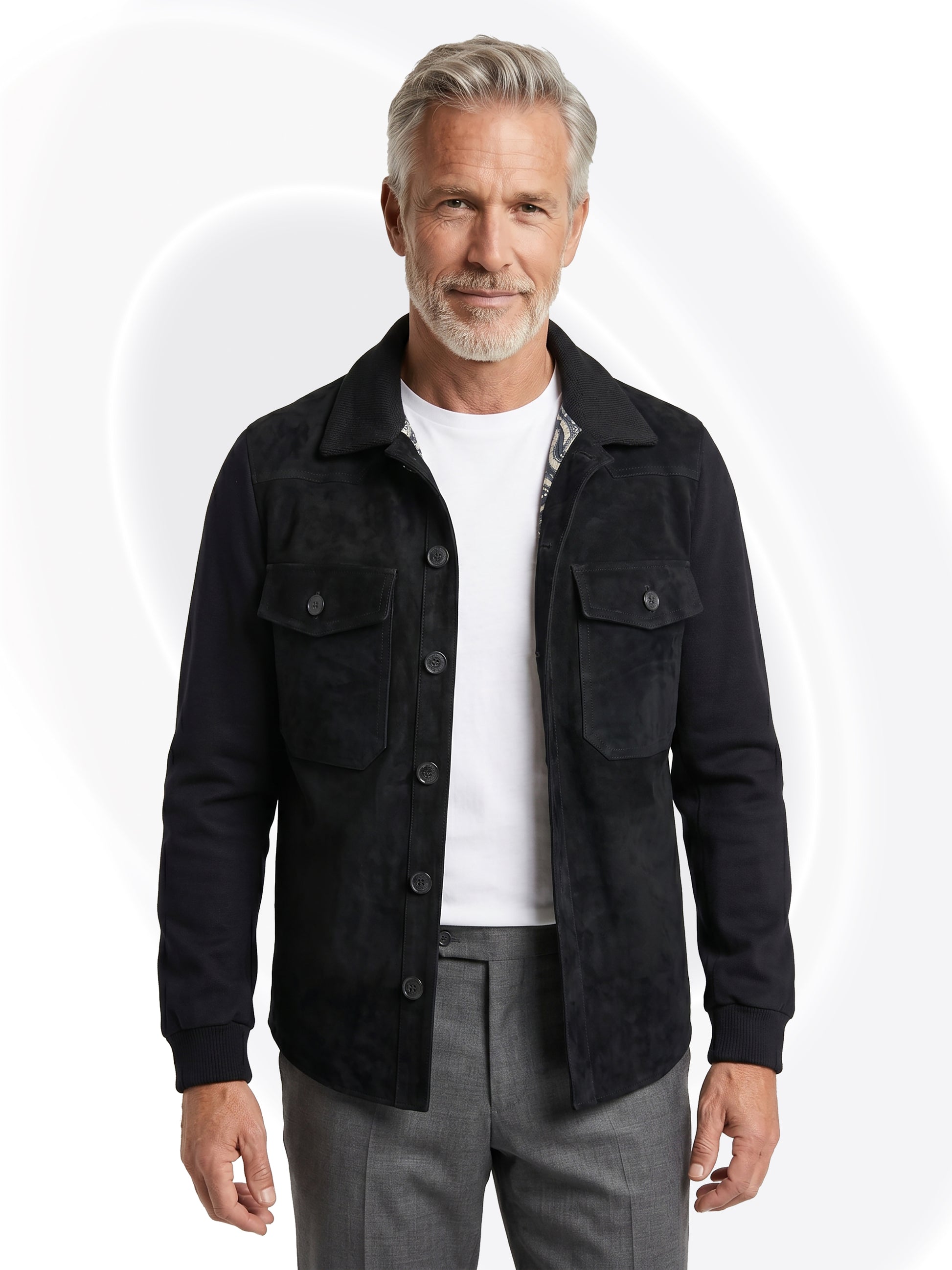 Man wearing a black suede jacket over a white shirt and gray pants on a white background