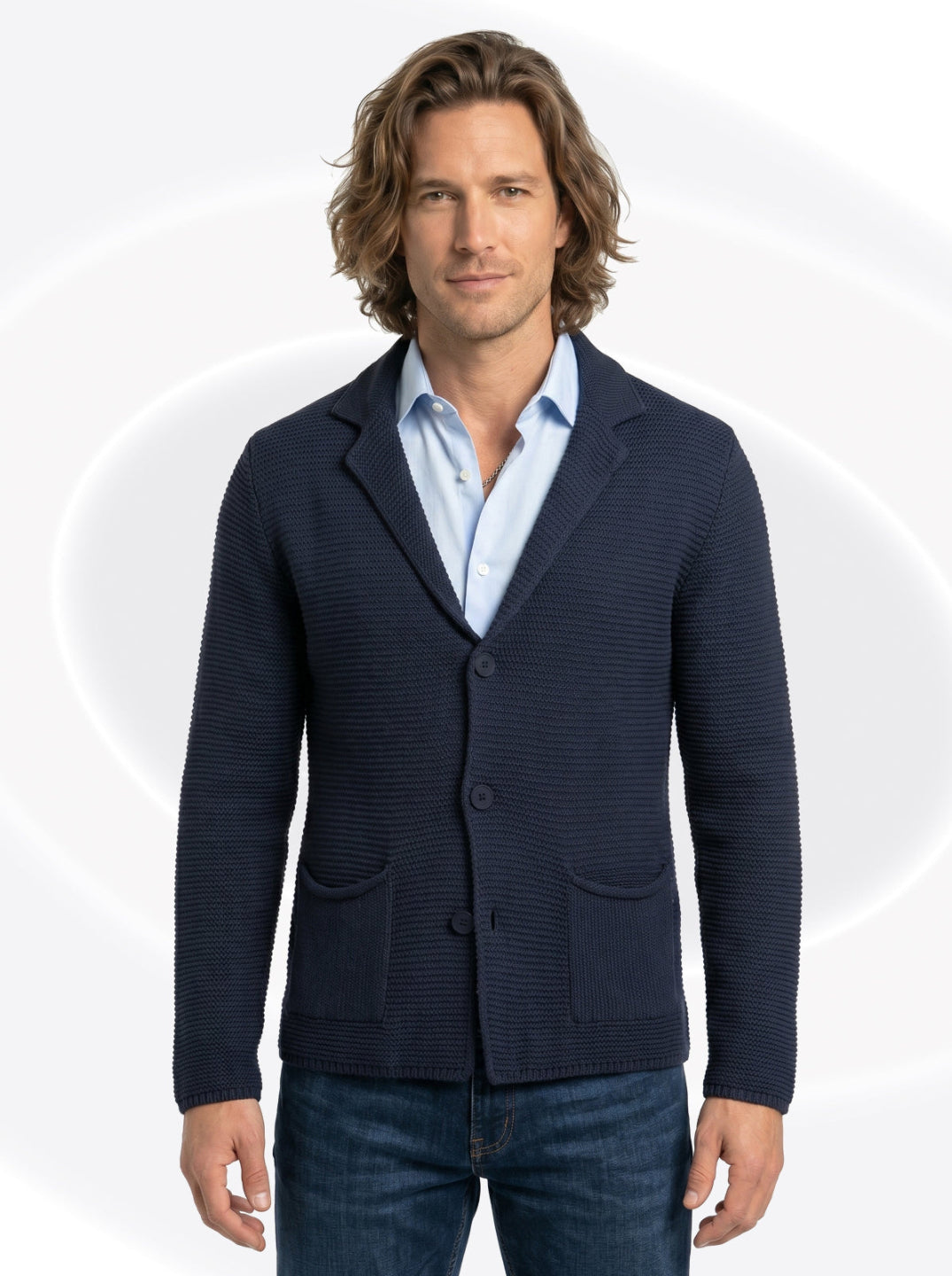 Man wearing a navy blue cardigan over a light blue shirt on a white background