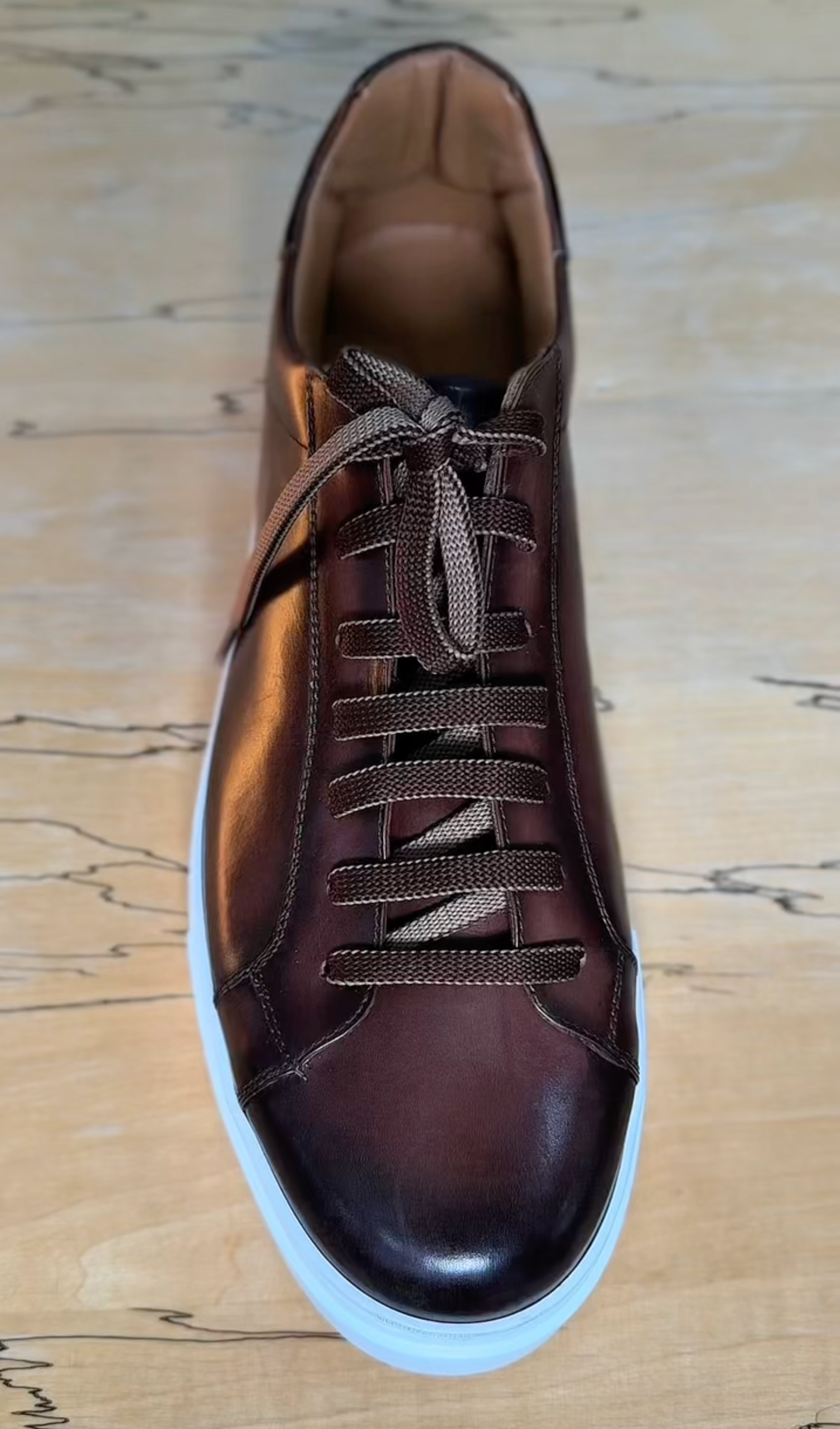 Brown leather sneaker on a wooden surface